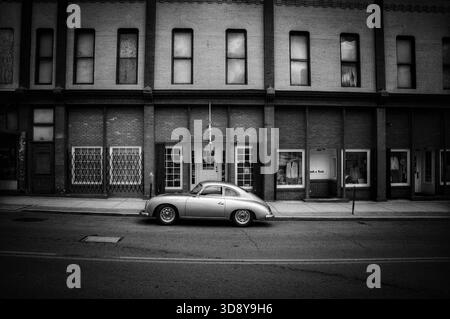 Porsche 365 d'epoca d'argento parcheggiata di fronte a un vecchio edificio in bianco e nero Foto Stock