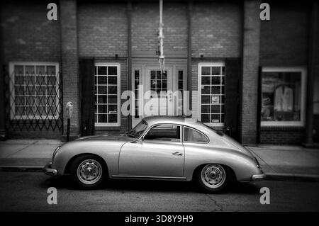 Porsche 365 d'epoca d'argento parcheggiata di fronte a un vecchio edificio in bianco e nero Foto Stock