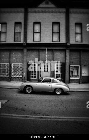 Porsche 365 d'epoca d'argento parcheggiata di fronte a un vecchio edificio in bianco e nero Foto Stock