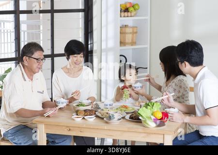 Famiglia asiatica che mangia a casa. Multi generazione che mangia e vive lo stile di vita Foto Stock