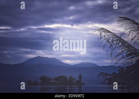 Le piccole di casa sulla piccola isola nel mezzo del meraviglioso Lago Maninjao al tramonto, nell isola di Sumatra, Indonesia Foto Stock