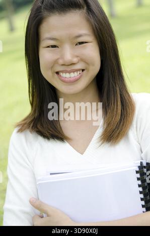 Studente universitario asiatico sorridente, in piedi all'aperto Foto Stock
