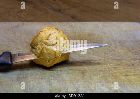 Eclari o ciambelle Principesse tagliate con un coltello seghettato su un asse di legno Foto Stock