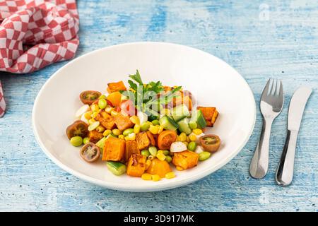 Insalata di patate dolci arrostite mescolata con mais, cetriolo ed erbe aromatiche Foto Stock