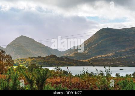 Ampia vista sul Lough Guitane, ripide pendenze di Cappagh Glen, altopiani autunnali, cielo suggestivo, Co Kerry Foto Stock