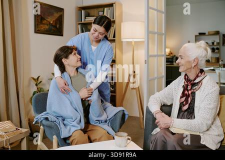 Donna di mezza età che conforta una donna anziana al chiuso Foto Stock