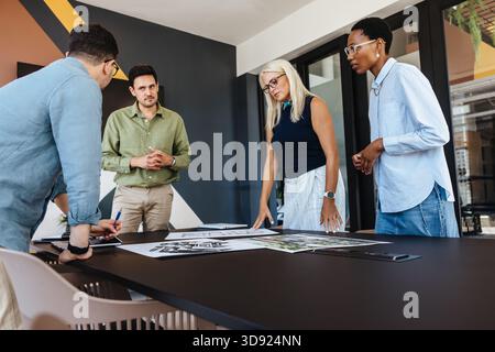 Un gruppo di diversi colleghi che discutono documenti durante una riunione formale in ufficio. L'area di lavoro presenta un design moderno che riflette un collabo Foto Stock