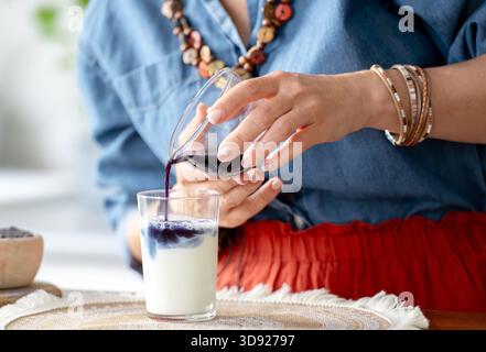 La donna versa Un Matcha latte con ghiaccio e latte in Un barattolo Foto Stock