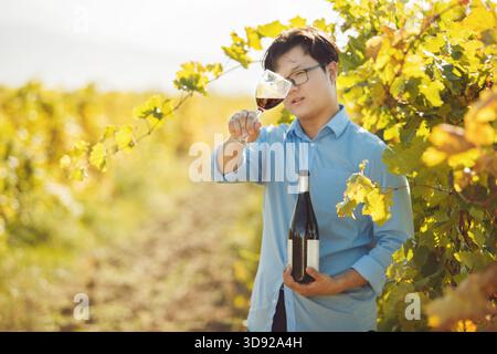 Sommelier maschio che tiene un bicchiere di vino rosso in cantina Foto Stock