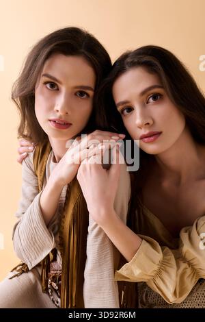 Due bellissime gemelle mettono in mostra i loro abiti eleganti mentre si posano insieme in armonia. Foto Stock