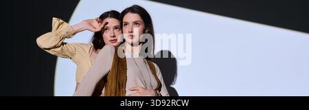 Le giovani gemelle sfoggiano il loro stile unico mentre sorprendono pose giocose in un ambiente dinamico. Foto Stock