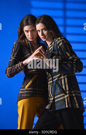 Due bellissime gemelle mostrano il loro stile alla moda mentre si combinano per una posa unica. Foto Stock