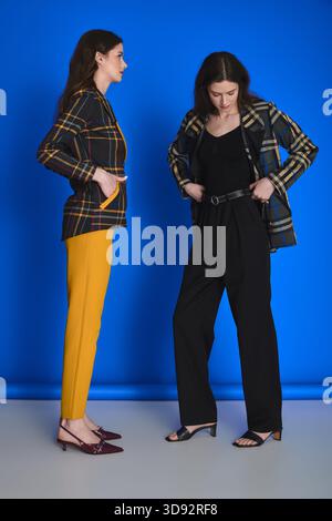 Due eleganti gemelle si sposano con sicurezza in abiti alla moda. Foto Stock