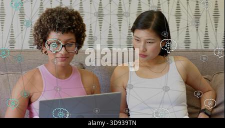 Collaborando con due donne in top senza maniche, gestendo un laptop sul divano nella sala con copertura ai Foto Stock