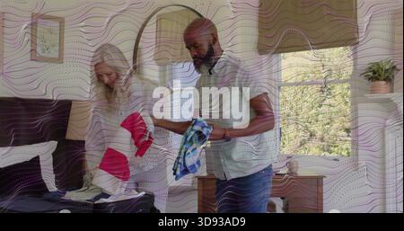 Confezionare una donna anziana e un uomo maturo, mettendo abiti a righe e blu in una valigia aperta sul letto Foto Stock