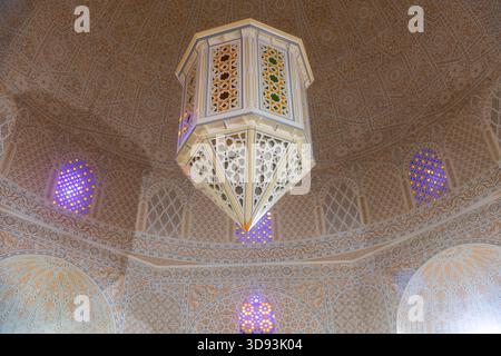 L'artigianato storico tunisino è rappresentato da un soffitto a cupola decorato e da una vista ravvicinata della cupola del mausoleo decorata in modo elaborato con una calda illuminazione ambientale Foto Stock