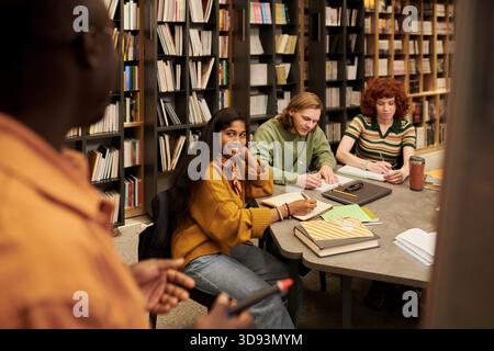 Gruppo multietnico di giovani che studiano insieme in ambiente Biblioteca Foto Stock