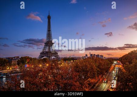 Vista panoramica al tramonto dello skyline illuminato di Parigi, in Francia, lungo la riva della Senna con la Torre Eiffel e il traffico stradale sfocato Foto Stock