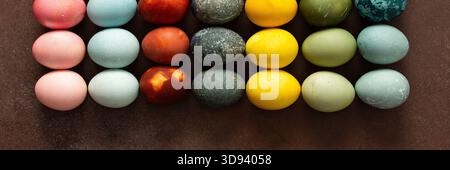 Le uova di Pasqua dai colori vivaci sono disposte in una griglia, con tonalità di rosa, blu, verde e giallo. Queste uova simboleggiano il rinnovamento e lo sono spesso Foto Stock