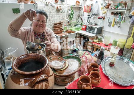 Città del Messico, Messico, Xochimilco, Dalia Restaurant Cafe, donna ispanica latinoamericana che prepara cucina tradizionale, mestolo pentola di argilla, cucina Foto Stock