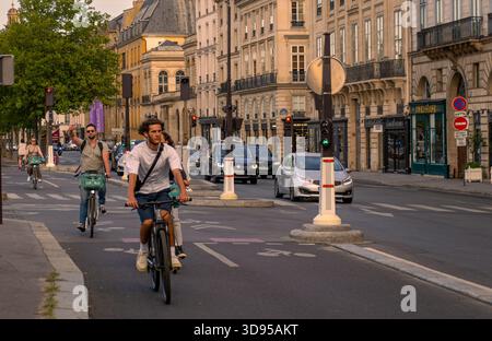 Parigi, Francia 08 04 2023: Vista del tramonto estivo su Quai Voltaire Street a Parigi, in Francia, con ciclisti in bicicletta sulla pista ciclabile. Foto Stock