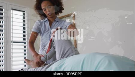 Sollevamento dell'infermiere centrale con una camicia blu che tiene la gamba del paziente anziano in camera da letto con sovrapposizione della mappa Foto Stock