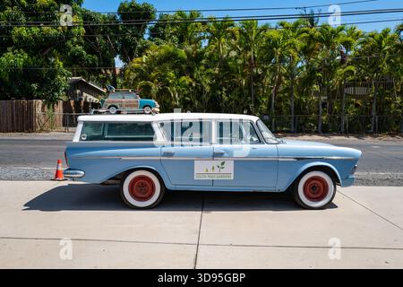 Station wagon retrò vintage blu chiaro con coprimozzo rossi e cartello South Maui Gardens. Station wagon in legno giocattolo con tavola da surf sulla strada vicino all'ingresso. Foto Stock