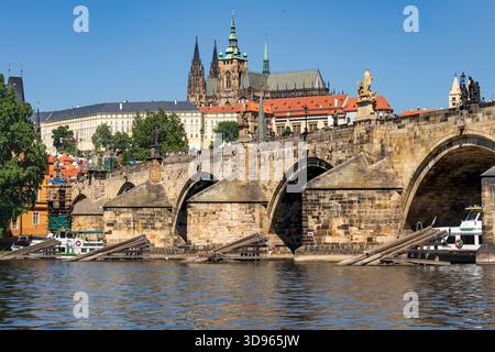 Praga, CZ - 4 giugno 2023 veduta del Ponte Carlo che attraversa il fiume Moldava con la Cattedrale di San Vito che si erge sopra il Castello di Praga sotto un cielo azzurro. Foto Stock