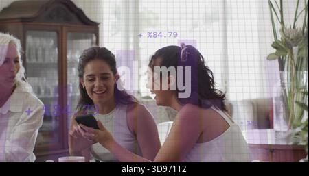 Due donne adulte che condividono lo smartphone in salotto, con armadietto porcellana e rivestimento viola Foto Stock