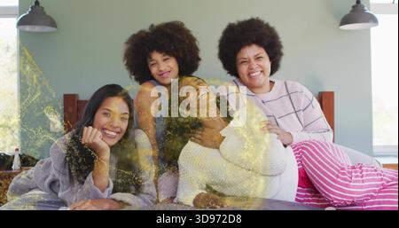 Raduna quattro donne che indossano un abbigliamento da salotto, toccano la pancia incinta sul letto a casa, scintillano Foto Stock