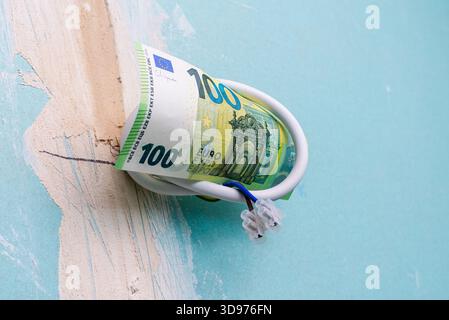 Impianto elettrico per la ristrutturazione dell'illuminazione, carta da 100 euro appesa ai fili di un vecchio appartamento, ristrutturazione dell'illuminazione di un appartamento residenziale con Foto Stock