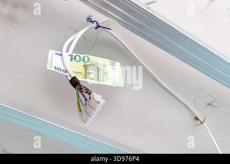 Impianto elettrico per la ristrutturazione dell'illuminazione, carta da 100 euro appesa ai fili di un vecchio appartamento, ristrutturazione dell'illuminazione di un appartamento residenziale con Foto Stock