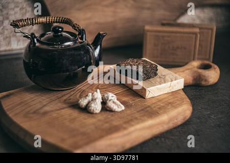 Una teiera d'argilla d'epoca artigianale che riscalda un tè cinese aromatico su una tavola liscia di legno di ciliegio, catturata in toni caldi che ne esaltano la consistenza, il vapore Foto Stock