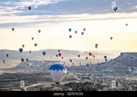 Goreme, Turchia - 19 aprile 2025: Veduta aerea di una moltitudine di mongolfiere che volano serenamente sul suggestivo paesaggio della Cappadocia, dipinto di wi Foto Stock