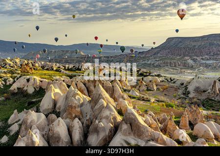 Goreme, Turchia - 19 aprile 2025: Veduta aerea di un paesaggio da sogno dove le vivaci mongolfiere punteggiano il cielo pallido sopra le formazioni rocciose ultraterrene di Foto Stock