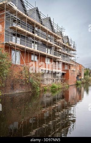 Sviluppo di un nuovo blocco a schiera multipiano di case residenziali in costruzione, con l'edificio circondato da impalcature. Alloggiamento Regno Unito. Foto Stock