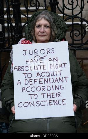 Londra, Regno Unito. 4 dicembre 2025. Gli attivisti di difendere le nostre giurie mettono in scena una veglia silenziosa fuori dalle reali Corti di giustizia, tenendo cartelli che affermano il "diritto delle giurie di assolvere” secondo coscienza. Si è svolta in vista di un ricorso giudiziario contro la condanna di cinque attivisti per il clima che hanno rotto le finestre della sede centrale della JP Morgan Bank a Londra nel 2021 per protestare contro il finanziamento delle banche di combustibili fossili. Quattro donne hanno ricevuto la sospensione della pena, mentre una è stata incarcerata per 12 mesi ridotta a 10. Crediti: Ron Fassbender/Alamy Live News Foto Stock
