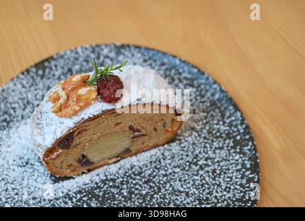 Fetta di delizioso Stollen, un tradizionale pane di Natale tedesco servito su un tavolo di legno Foto Stock