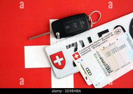 Targa Svizzera e chiave di accensione sulla bandiera svizzera primo piano. Patente di guida e concetto di immatricolazione Foto Stock