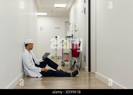 Sedia a rotelle di colore marrone e carrello medico rifornito sono seduti nel corridoio dell'ospedale vicino ai segni di imaging Foto Stock