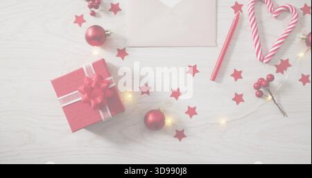 Scatola rossa con nastro bianco e arco su un tavolo in legno chiaro, con cuore di canna da zucchero Foto Stock