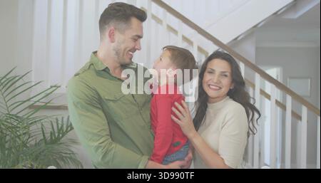 Tenendo il padre che culla il figlio all'ingresso di casa, con scala delle piante e maglia verde color crema Foto Stock