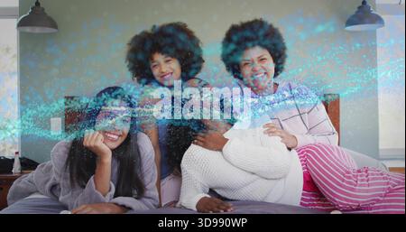 Quattro donne sdraiate che indossano pigiami e poltrone sul letto in camera da letto, con rivestimento blu Foto Stock