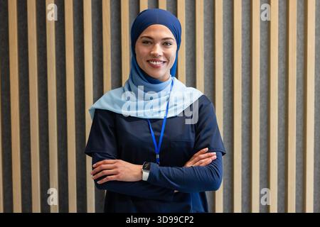 Lavoratore sanitario femminile in piedi centrato in clinica che indossa scrub della marina, velo, cordone blu Foto Stock