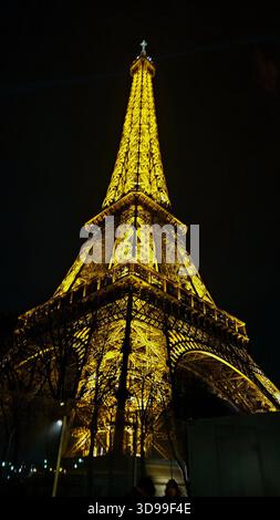 Torre Eiffel illuminata di notte a Parigi, Francia, con luci dorate e una spettacolare vista dall'angolo basso. Foto Stock