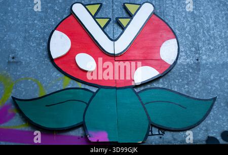 Murale di Street art a Berlino che mostra una pianta carnivora ispirata al motivo "Piranha Plant" della serie di videogiochi Super Mario, uso editoriale Foto Stock