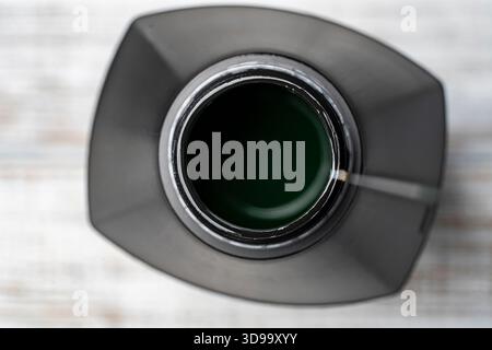 Contenitore dell'olio motore su sfondo di legno bianco, primo piano, vista dall'alto. Aprire l'olio motore nel recipiente di plastica Foto Stock