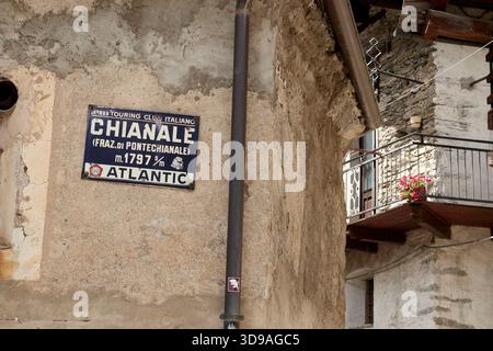 Cartello stradale sul lato di un vecchio edificio in pietra. Chianale, Cuneo, Piemonte, Italia Foto Stock