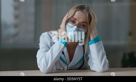 Stressata sonnolenza burnout donna caucasica medico in viso protettivo maschera medica operatore medico stanco ragazza esausta infermiera donna praticante sensazione Foto Stock