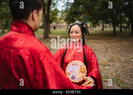 Coppie multiculturali che celebrano la tradizione dei matrimoni asiatici nel parco Foto Stock
